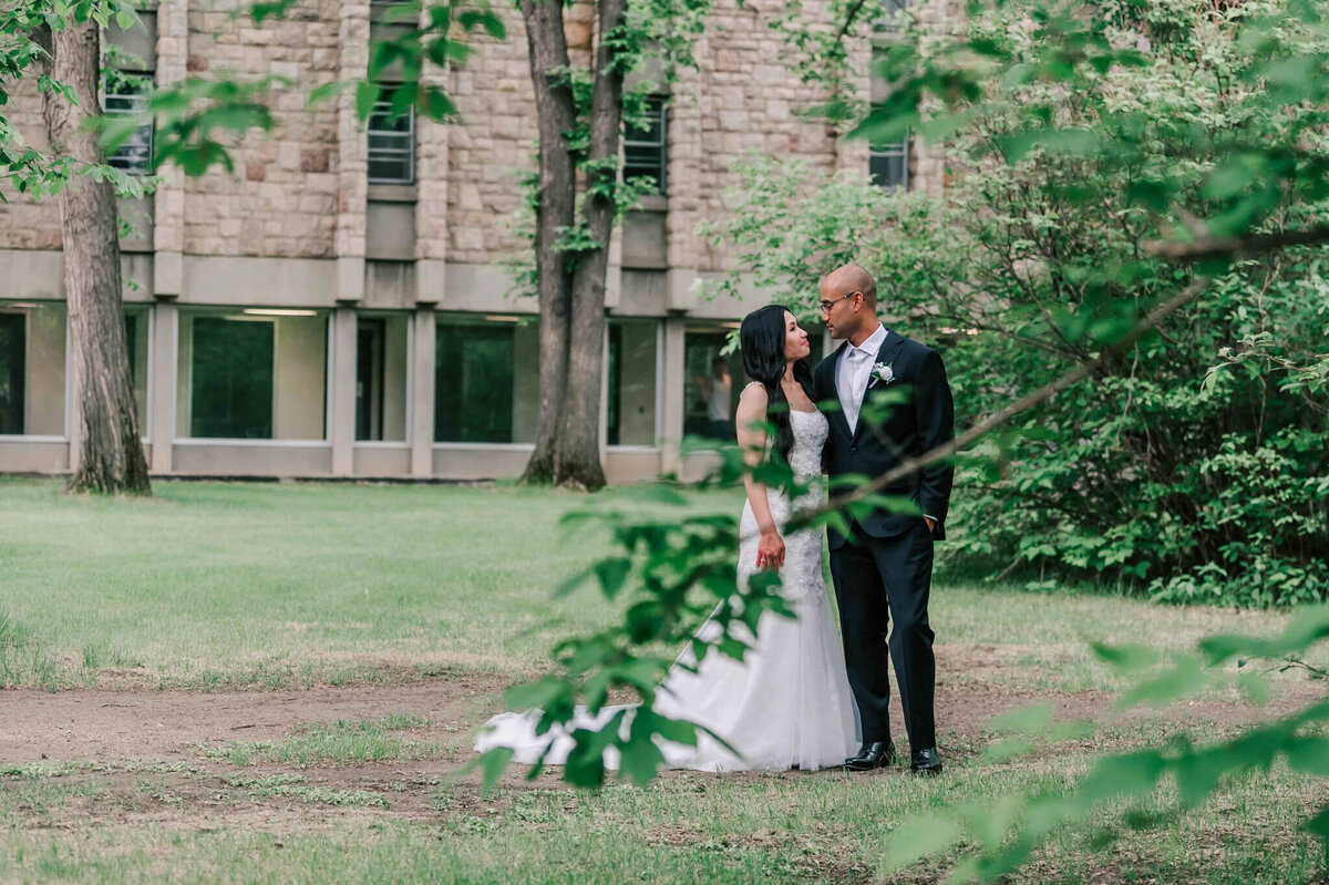 Bride and groom stand beside each other looking at each other. 