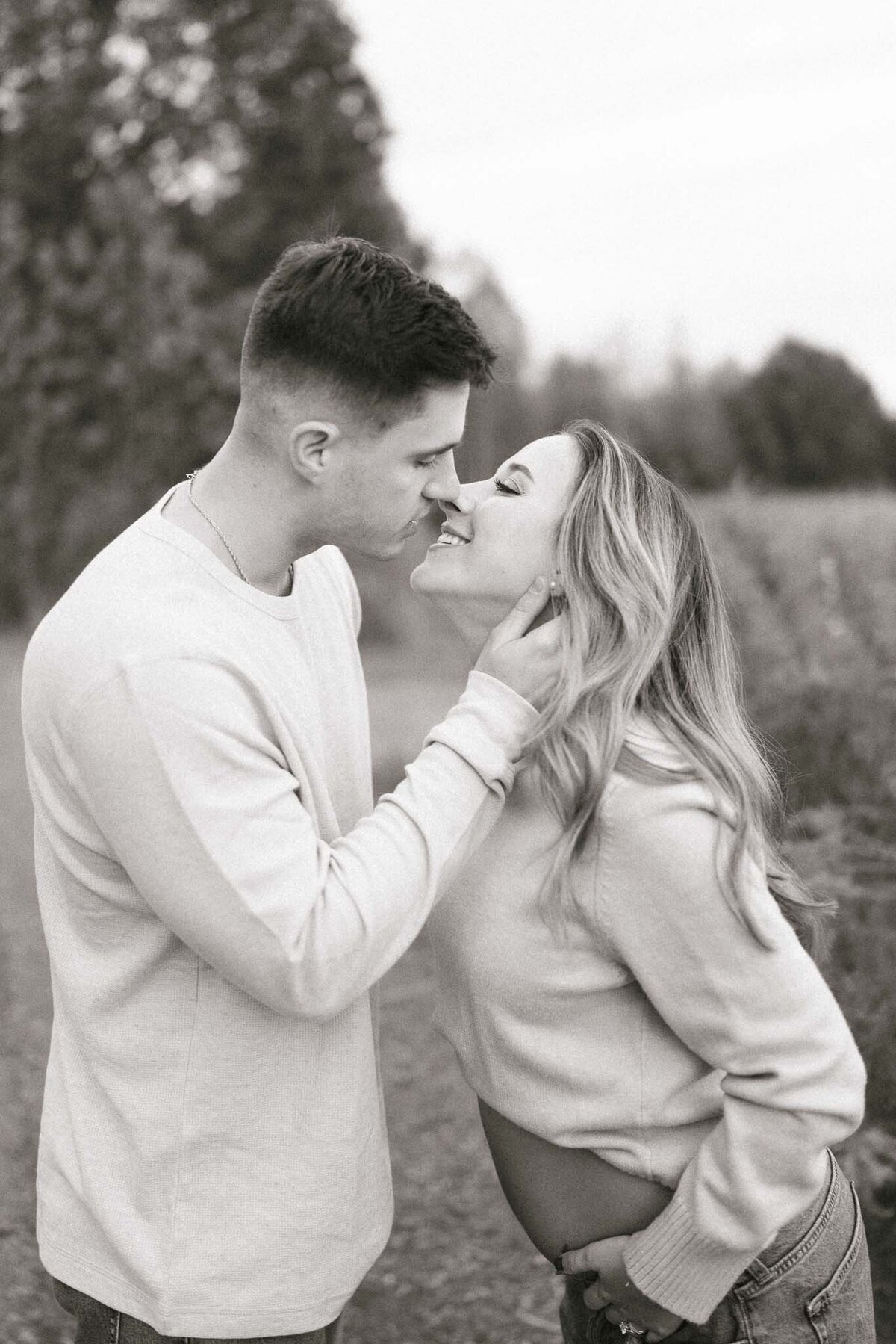 man and pregnant woman kiss at seven islands state birding park in october near knoxville tennessee
