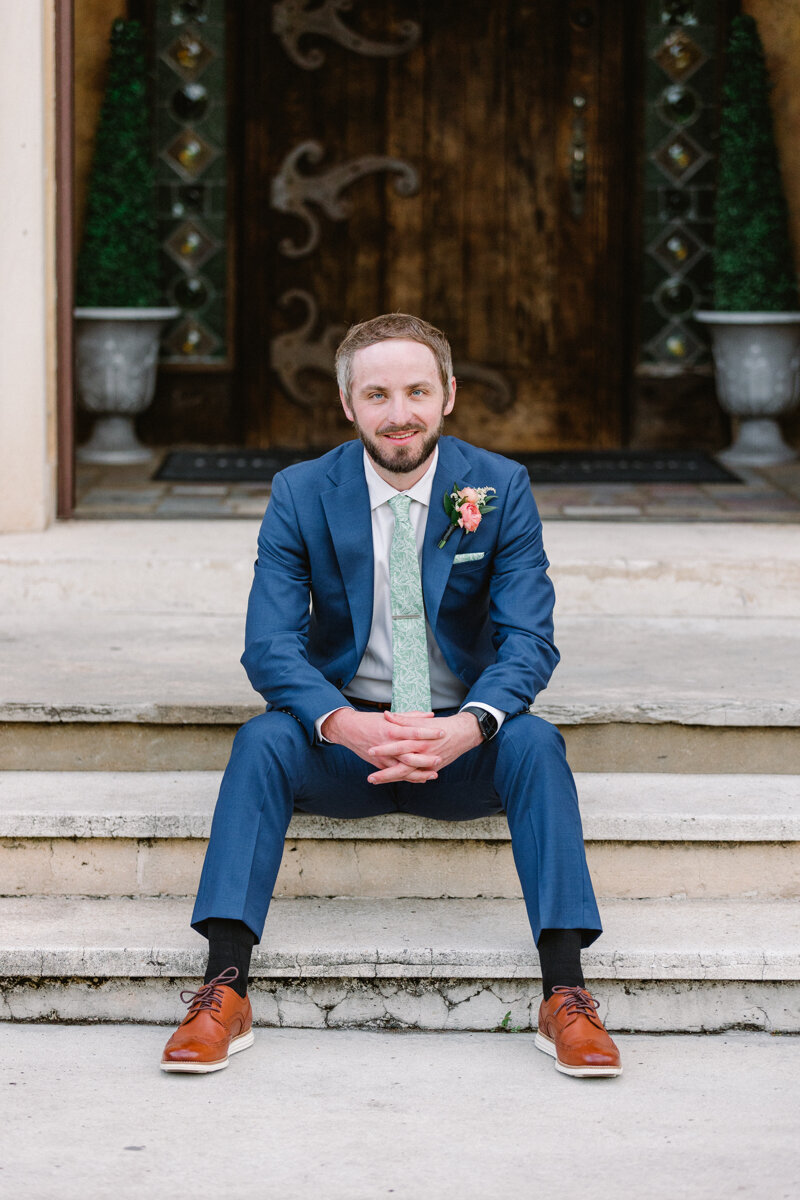 groom sitting on steps of howey mansion