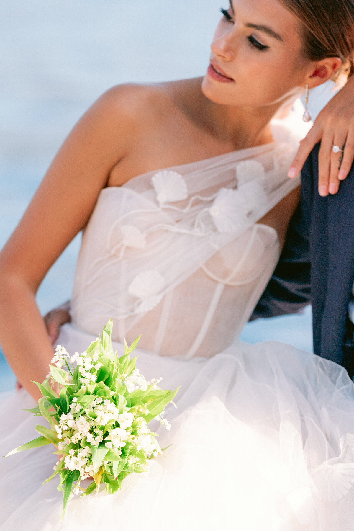 Bride holding a small bouquet of white florals with greenery with groom