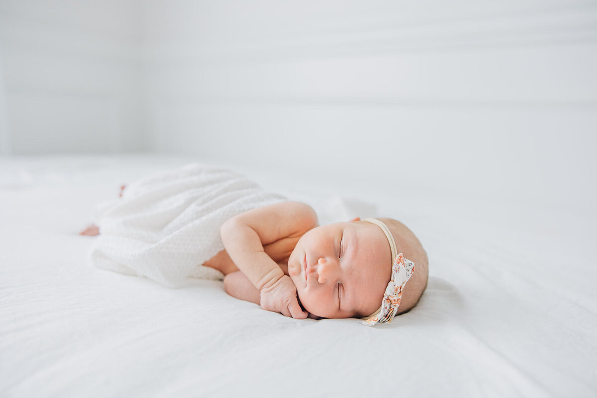 baby girl sleeping on bed wrapped in white cloth