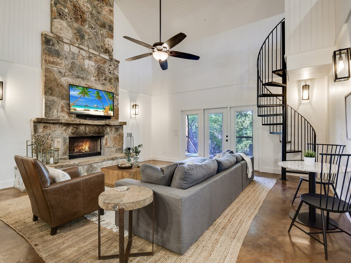 Cabin living room with large fireplace and spiral staircase