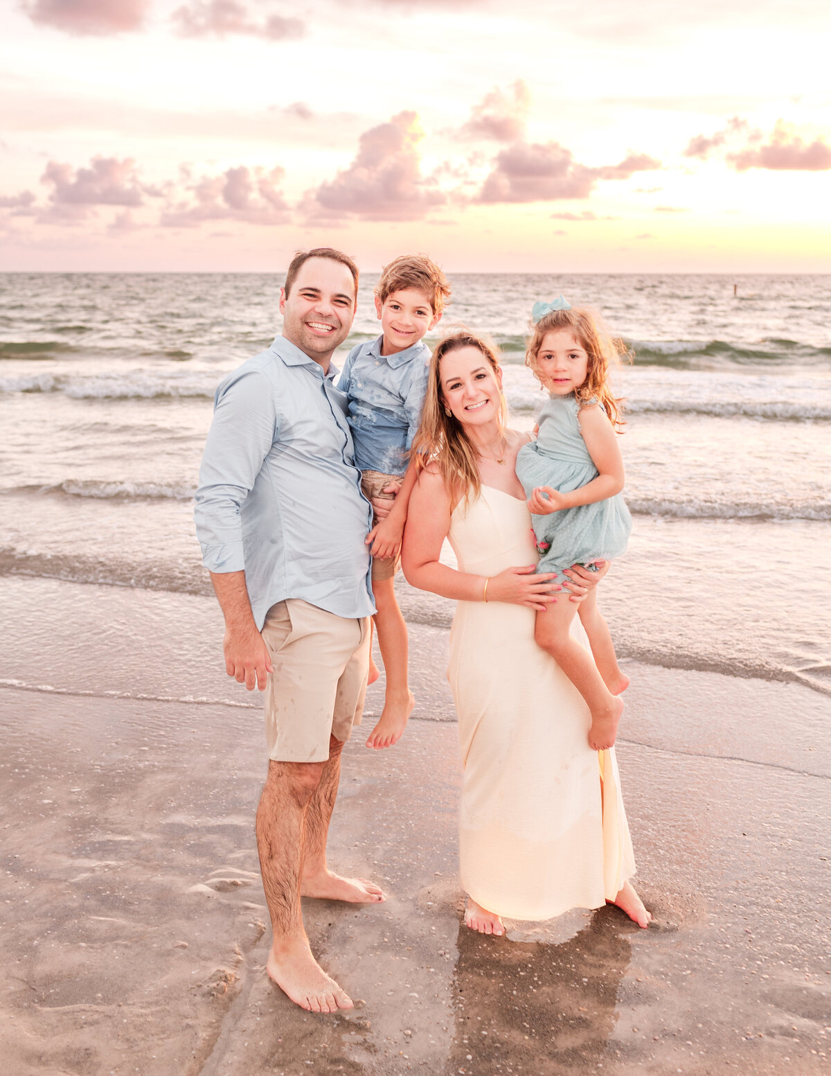 Extended family posing at Clearwater Beach during golden sunset.