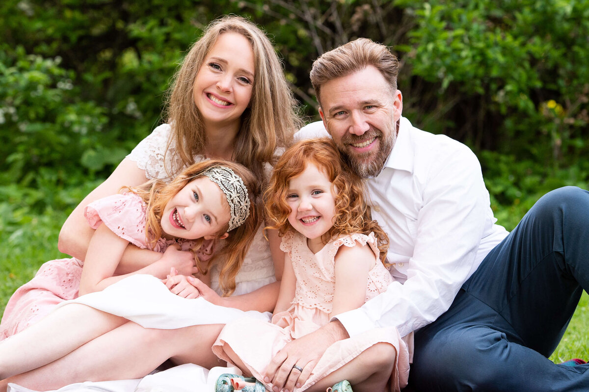 mom and dad cuddle their children sitting on a blanket.  Taken by Ottawa Family Photographer JEMMAN Photography