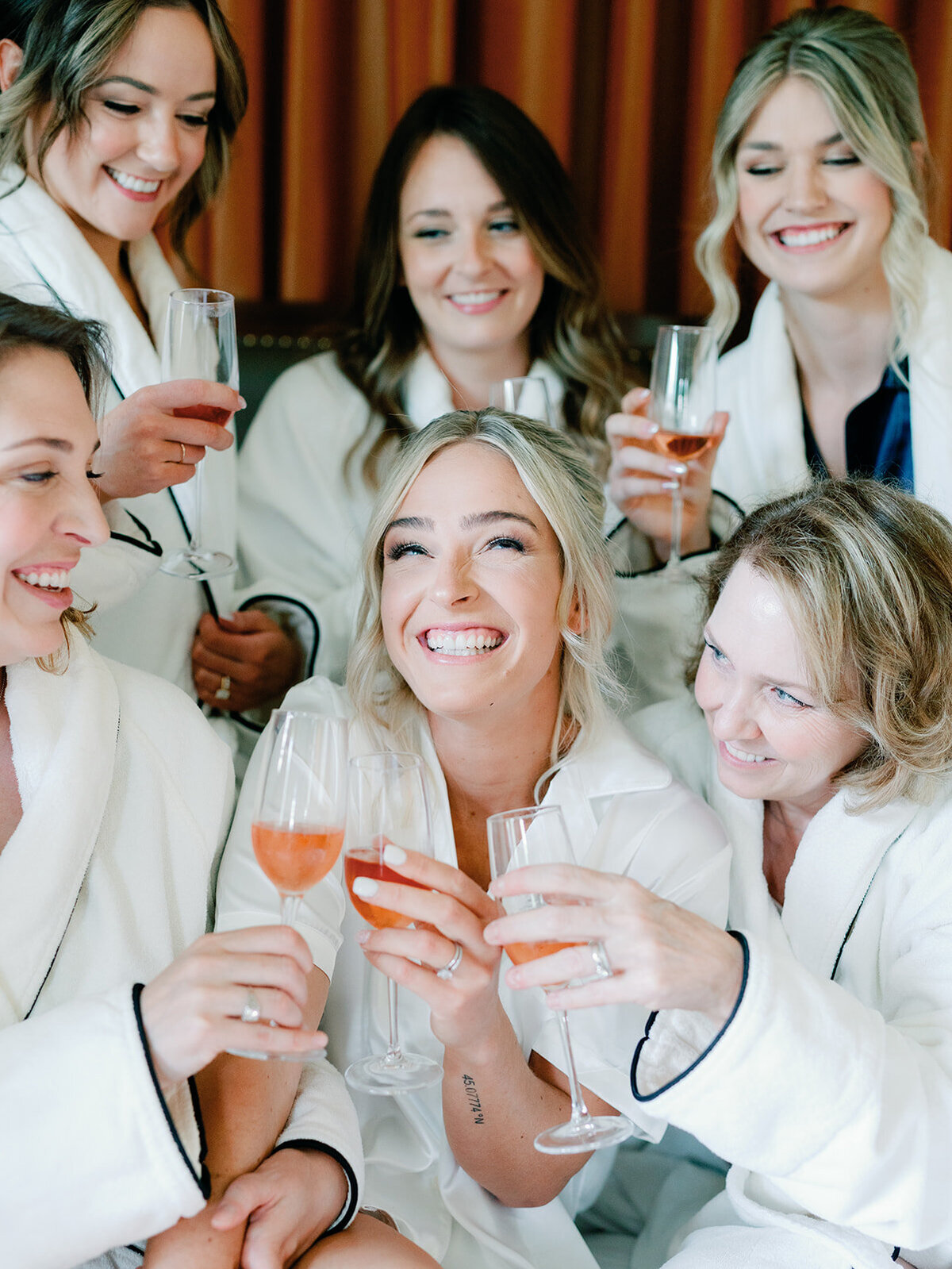 Bride elated as she is surrounded by her bridesmaids cheering with champagne