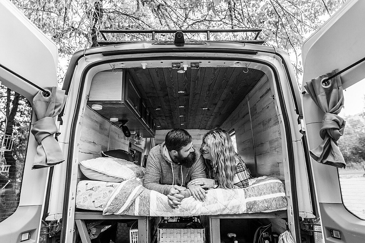 Couple laying in the back of a campervan
