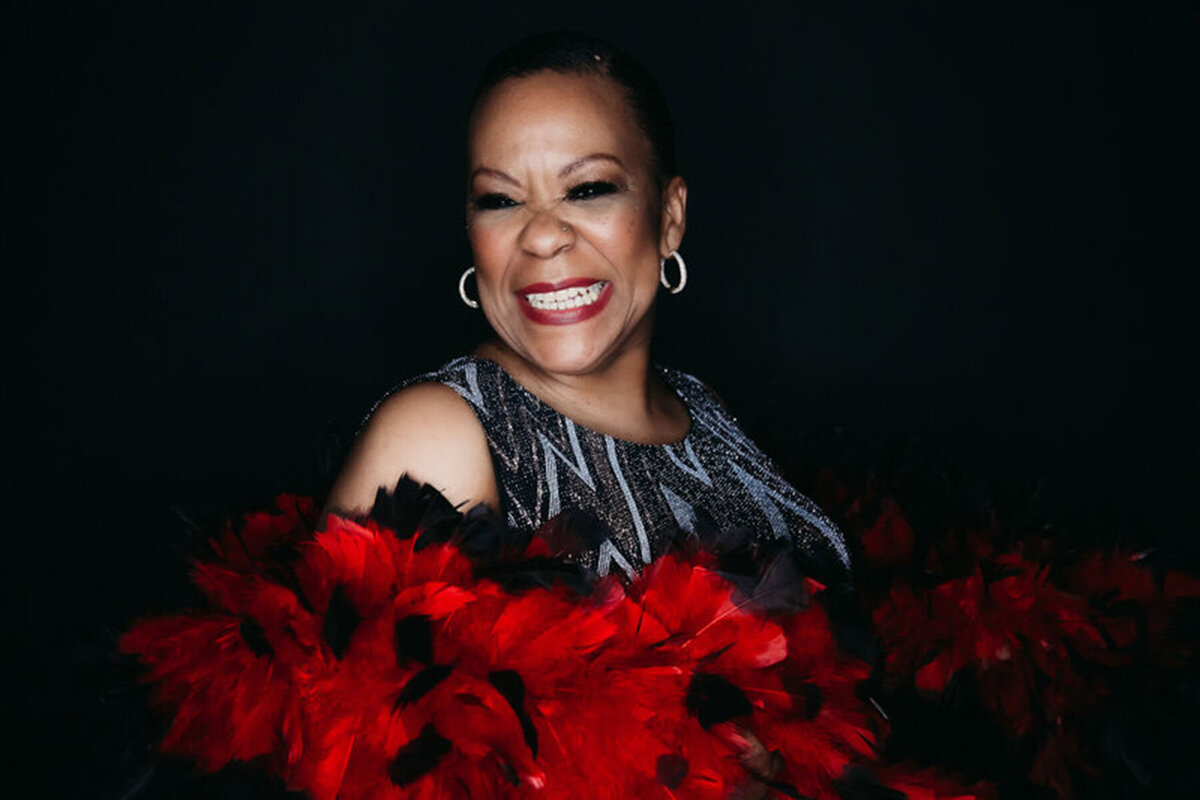 Dark and moody portrait of older black woman wearing red and black boa