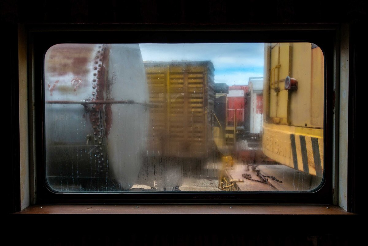 A fogged train car glass window with condensation looks out on a train yard scene