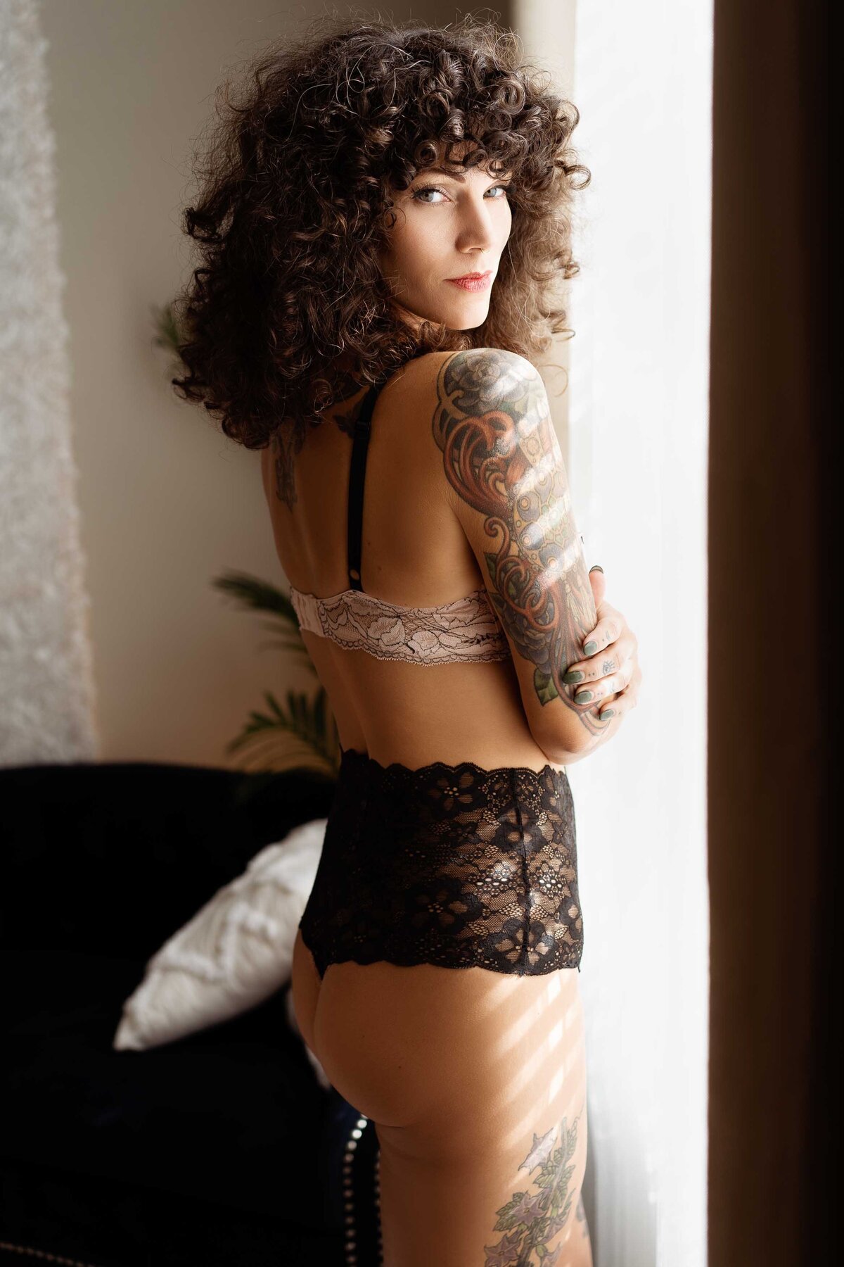 sexy woman with tattoos standing by a window
