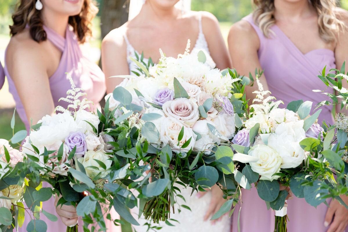 Bride with bridesmaids holding white florals with greenery at wedding at Stones River Country Club