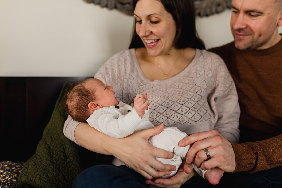 Infant photography of a mom holding new born baby, with dad holding arms around mom.