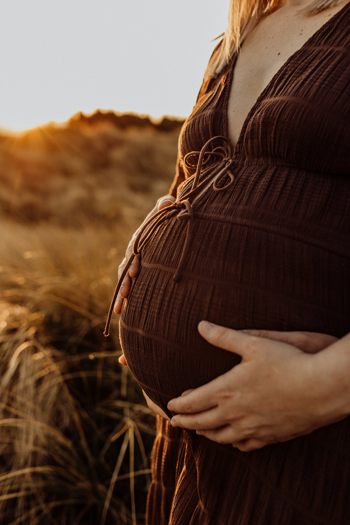 A close up of a pregnant belly with both parents hands in the photograph, a popular shot requested by mothers in christchurch