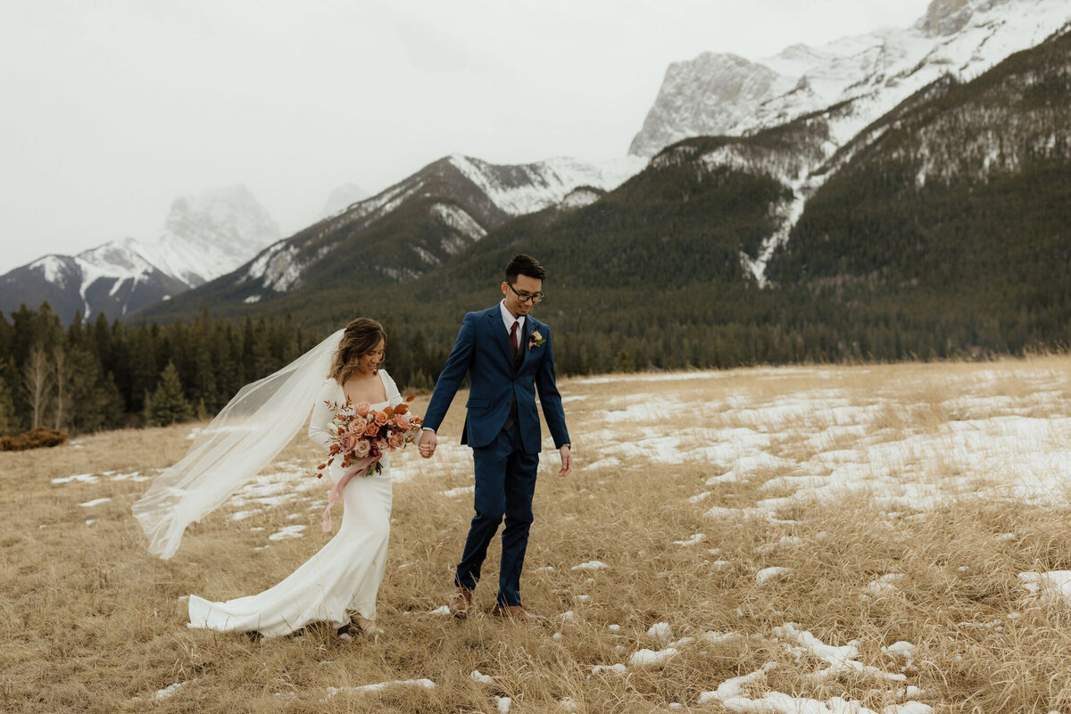 Bride and groom walking in the mountains, by Malorie Reiter Photography, adventurous and authentic wedding photographer in Lethbridge, Alberta. Featured on the Bronte Bride Vendor Guide.