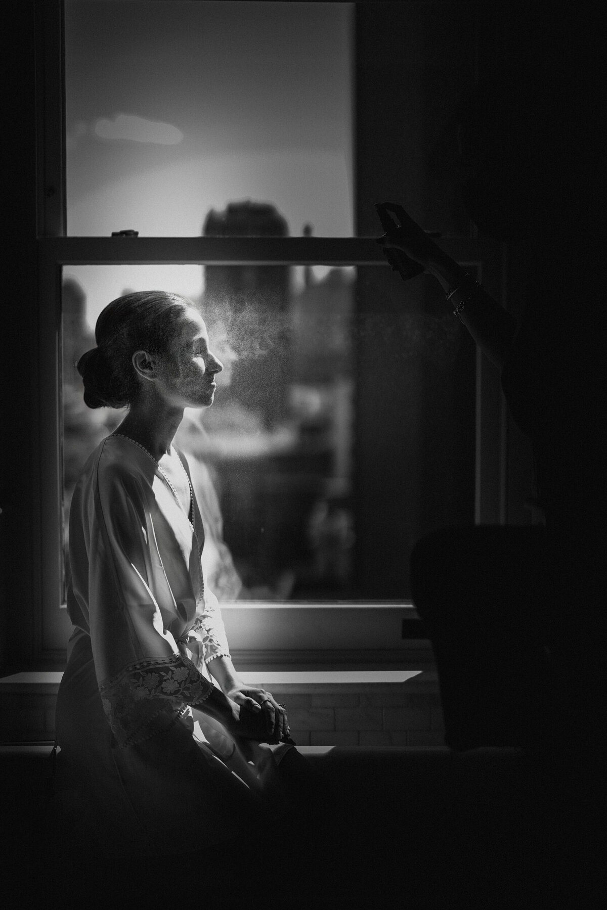 A bride gets makeup done at the window at a Beekman Hotel wedding