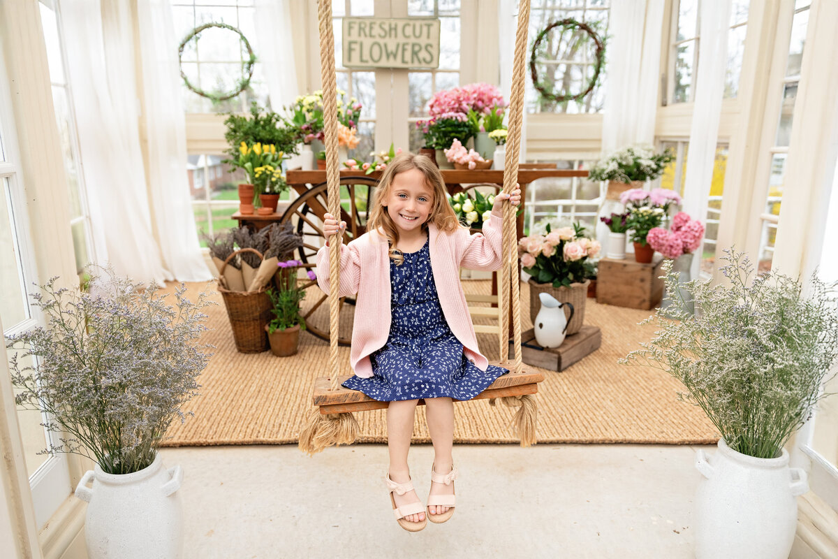 Spring portrait of young girl swinging inside floral greenhouse setup | All Who Wander Flower Farm in Dundas Ontario photographer