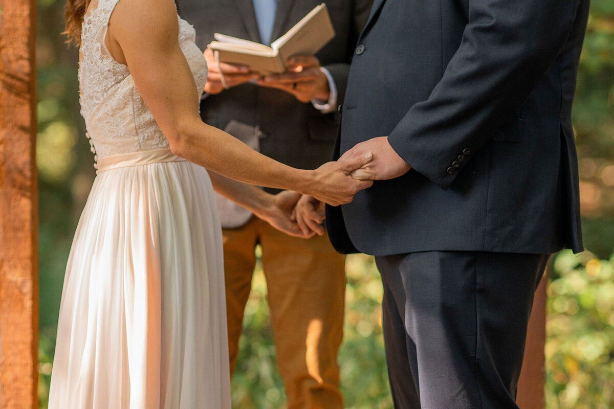 Bride and groom holding hands during their outdoor ceremony.