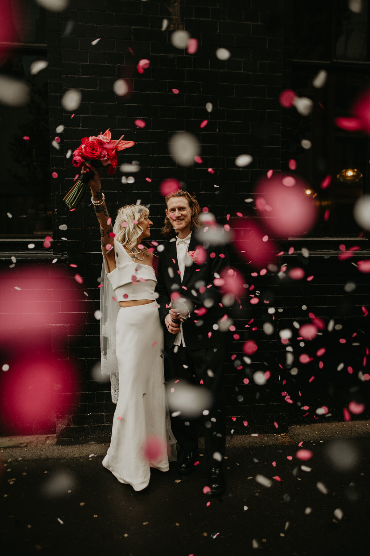 A bride and groom pop a pink and white confetti cannon outside Northern Monk Refectory in Manchester's Northern Quarter. 