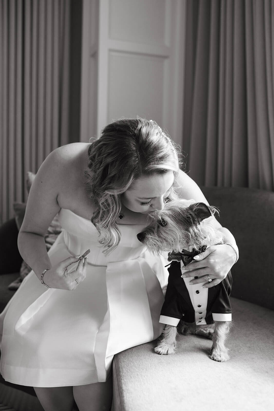 Bride holding her dog while getting ready at St. Regis Aspen, sharing a sweet moment in a sophisticated, light-filled suite.