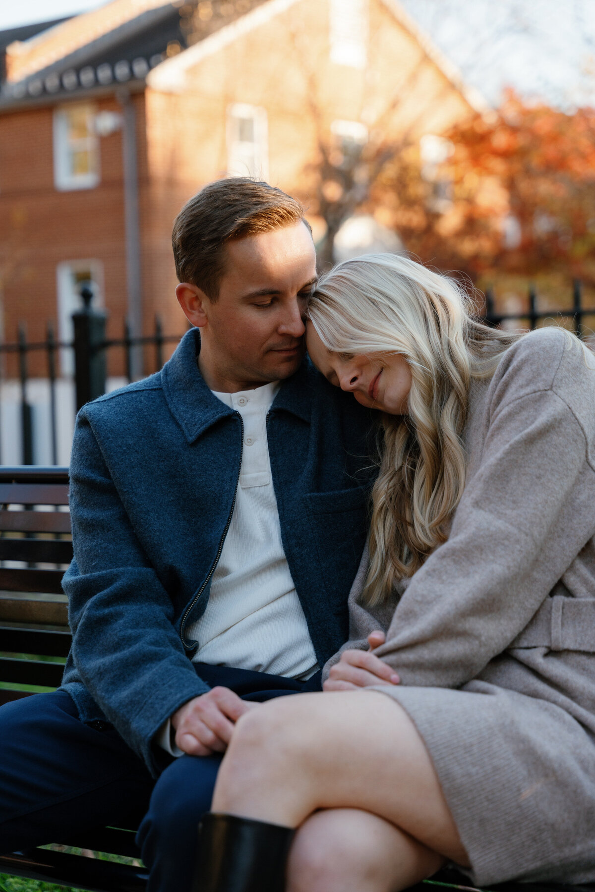 A person sitting on a bench resting their head on their partner's shoulder