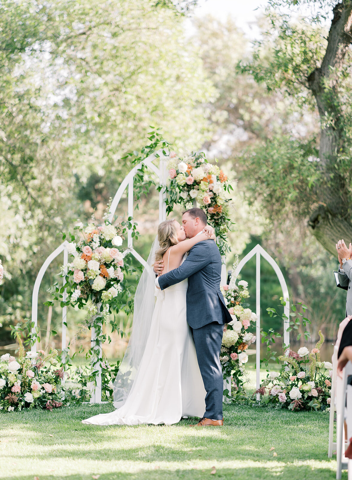 bride and groom kiss at outdoor wedding ceremony on lawn