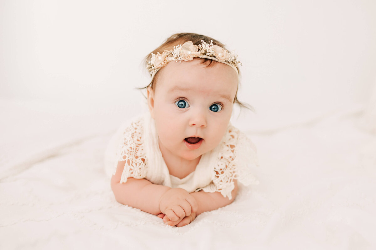 little girl in floral crown on bed in Springfield MO baby photography session