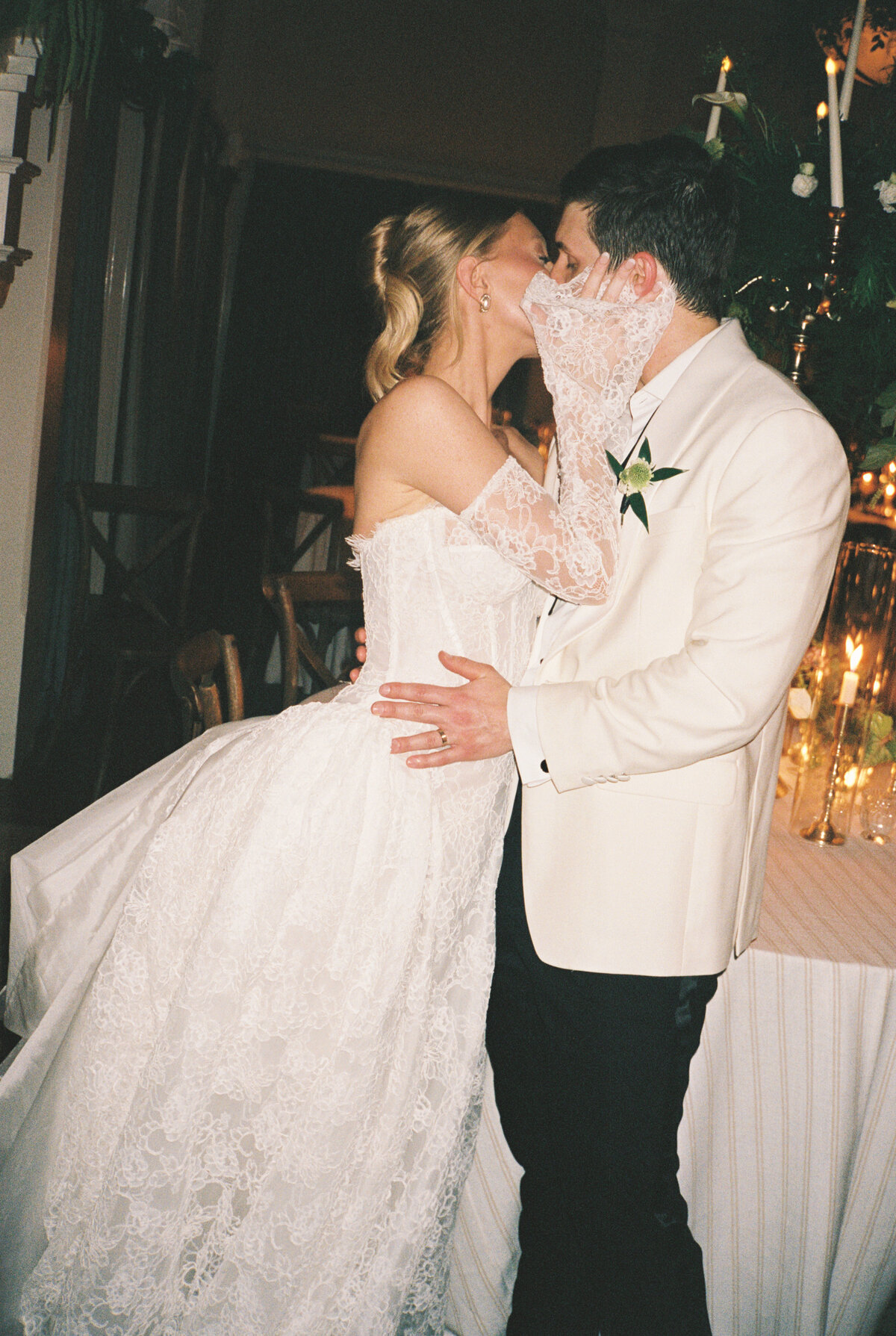 Newlyweds kiss under candlelight at  their wedding reception