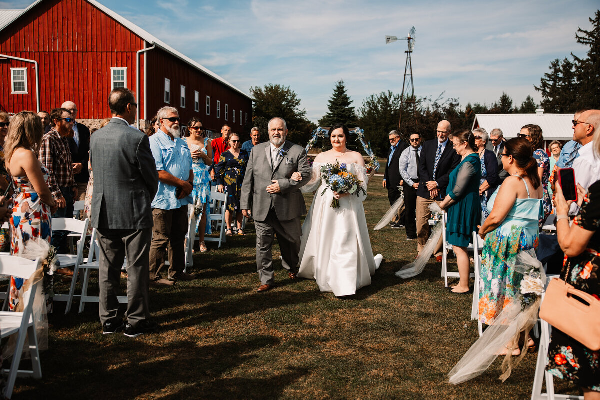 A father walks his daughter down the aisle for her outdoor wedding ceremony