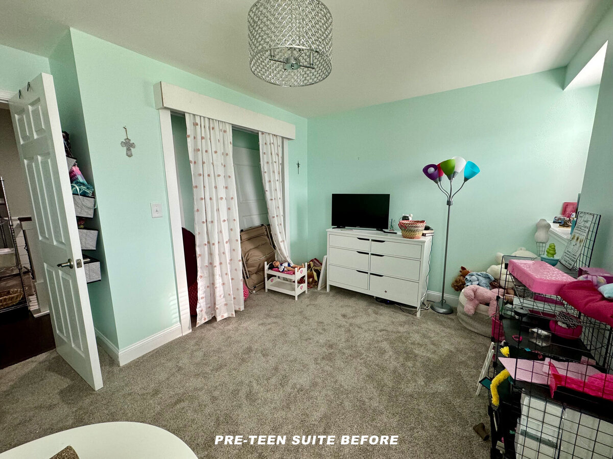 A neatly organized pre-teen bedroom with light green walls, a carpeted floor, and a white dresser holding a small TV. There’s a colorful floor lamp, a closet with a curtain, and various stuffed animals. Text reads "PRE-TEEN SUITE BEFORE.