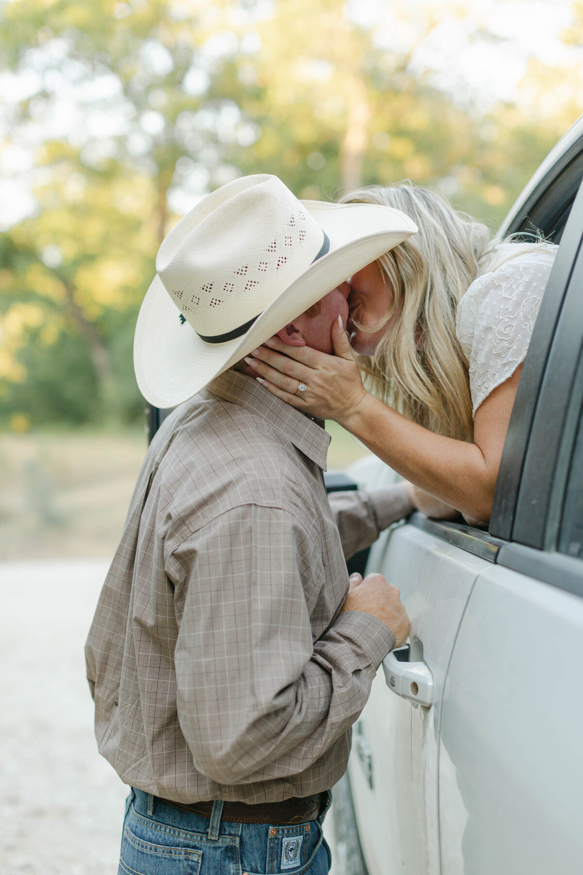 engaged couple kissing next to pickup truck