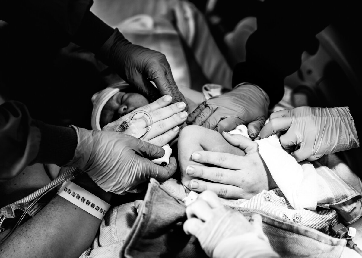 Many hands birth photography in hospital newborn baby