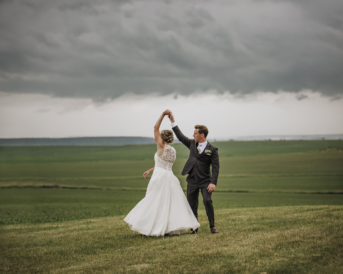 Bride and groom share a romantic dance in a serene field under a dramatic sky taken by jen Jarmuzek photography a Minneapolis wedding photographer