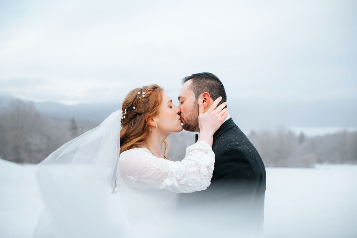 winter elopement bride and groom kissing in snow at mountain top inn in chittenden vermont