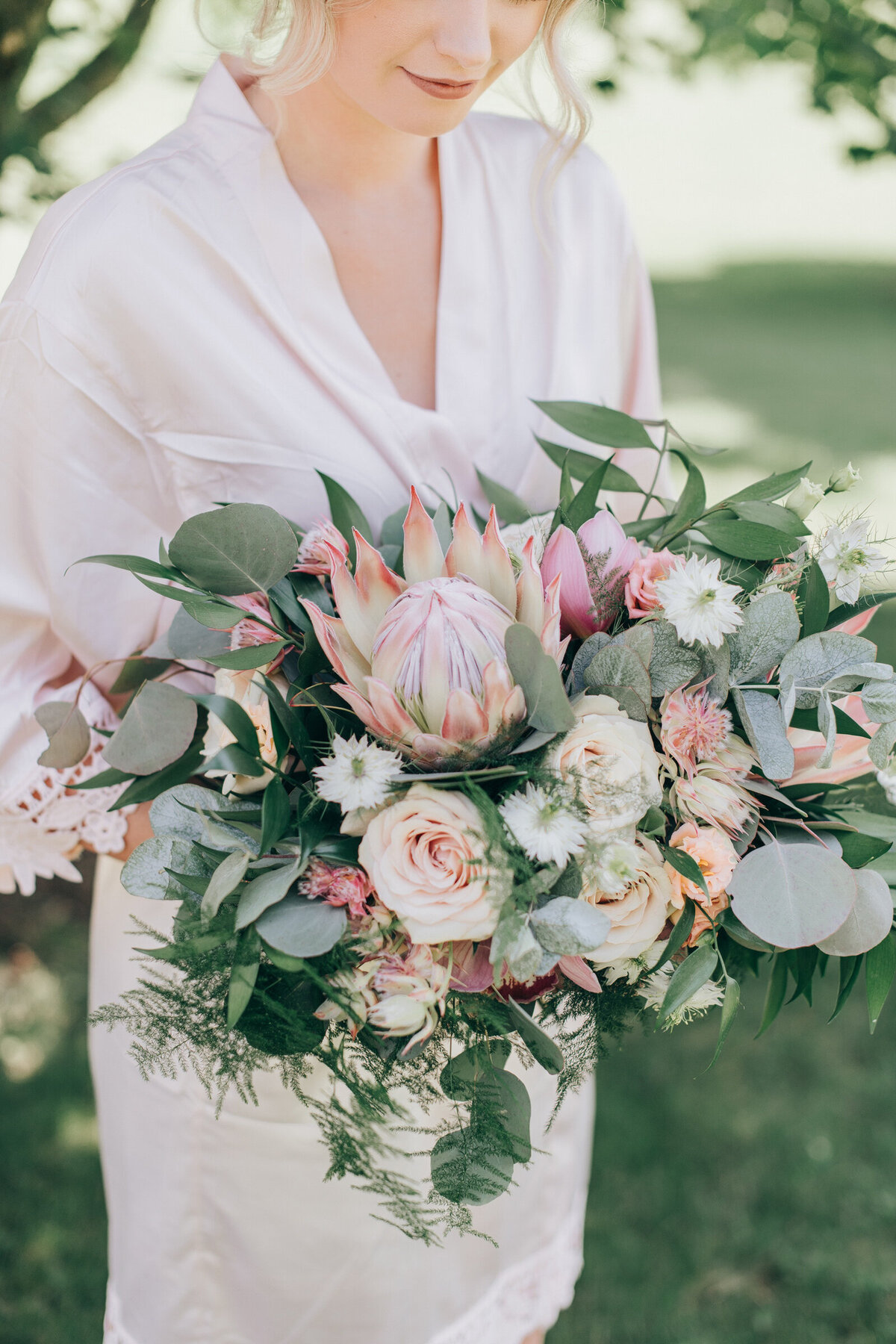 A whimsical wedding bouquet with exotic pink flowers, ivory roses and green eucalyptus