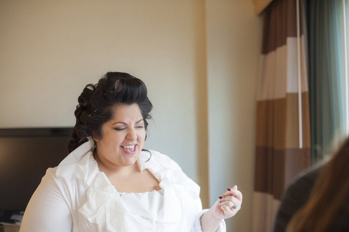 A person in a wedding dress smiling as they get ready 