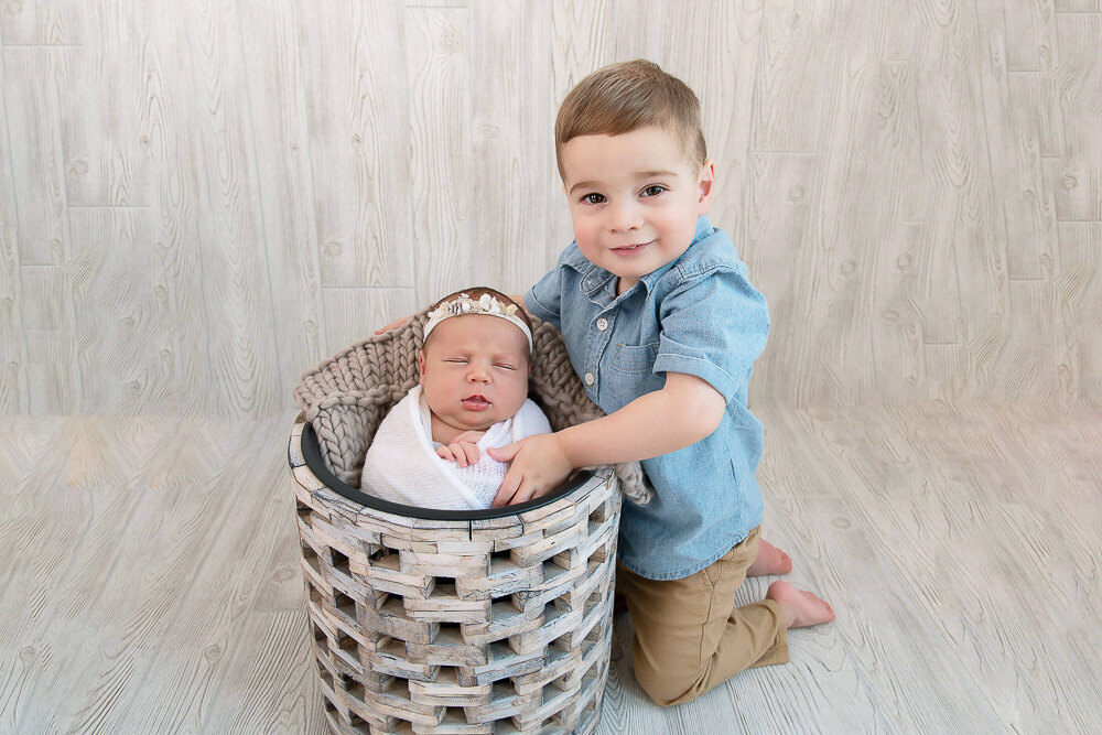 Big brother with his newborn baby sister in a bucket.