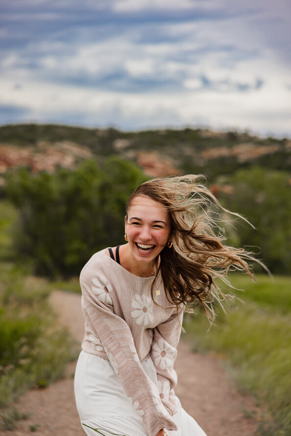 Girl leans over and laughs as wind blows her long hair.