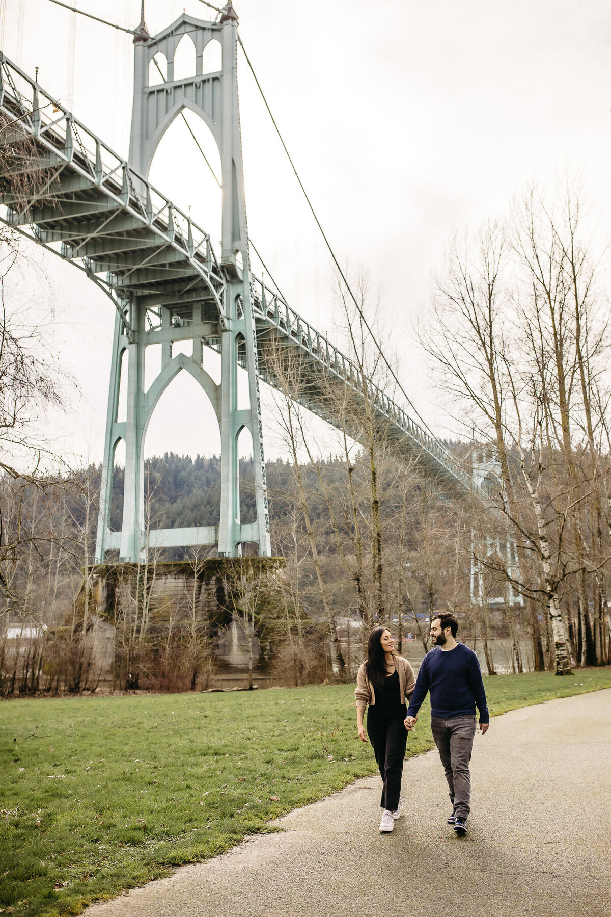 Couple walks holding hands at St Johns Bridge in Portland Oregon