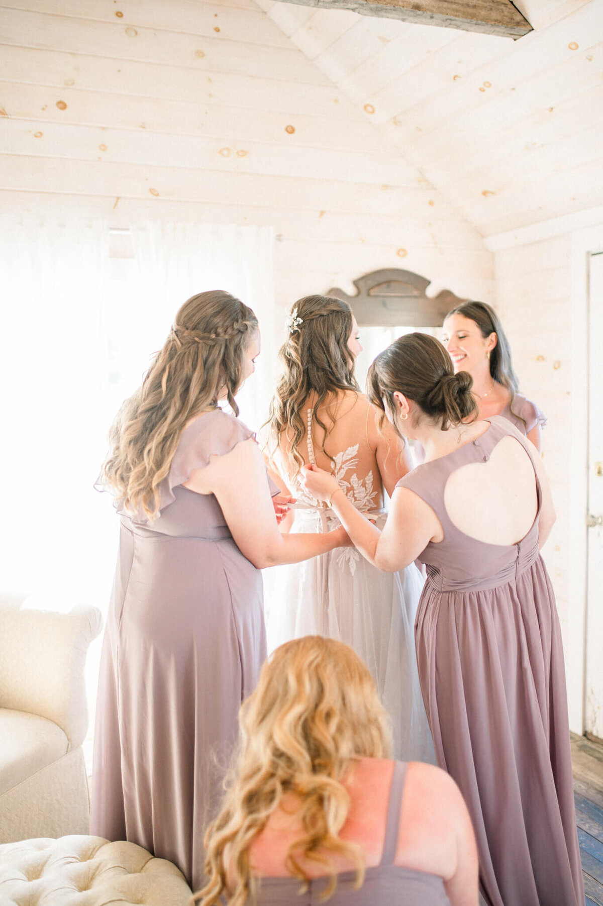 Bridesmaids helping bride adjust her dress one last time before the first look