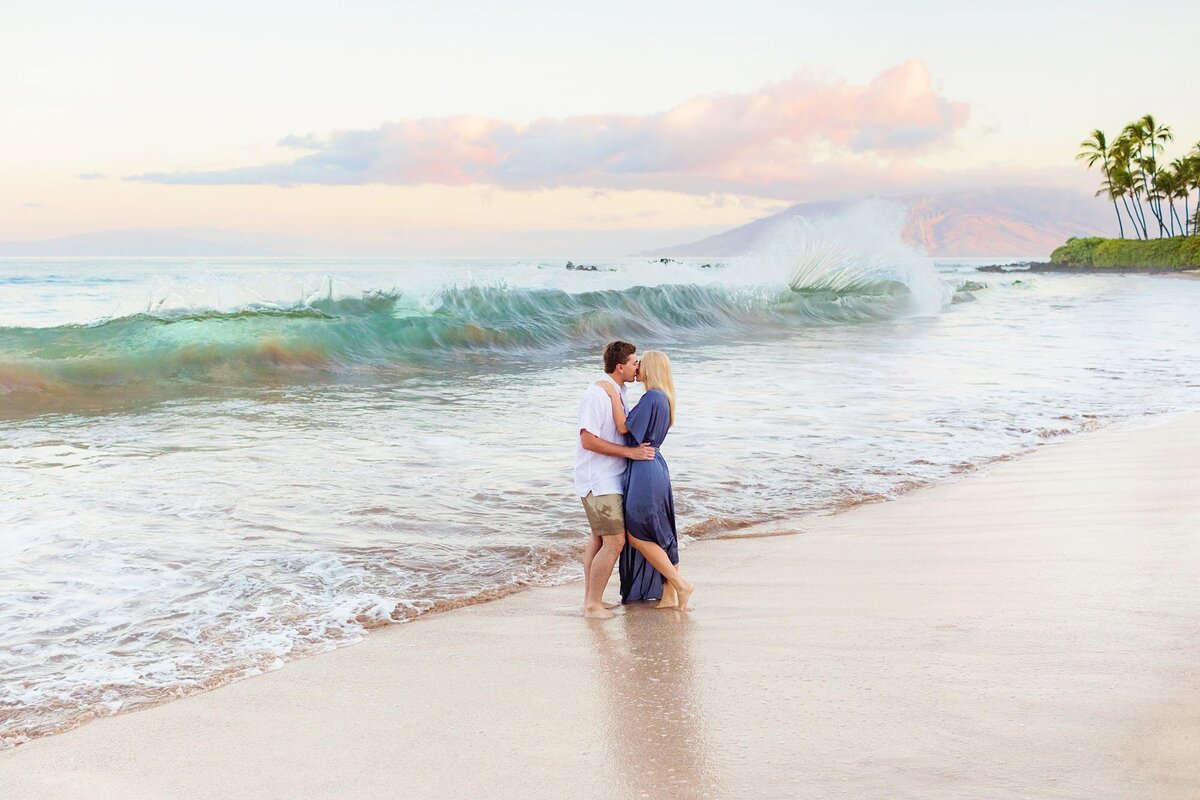 Powerful shorebreak behind a couple having Maui engagement portraits taken by Love + Water at the beach