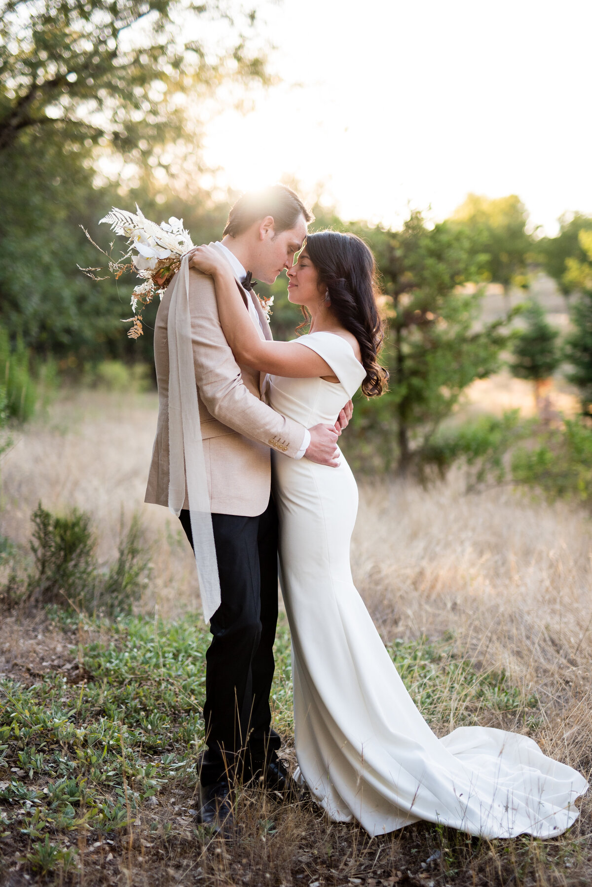 Bride and groom embrace as they go in for a kiss during golden hour at Swan Lake Mansion.