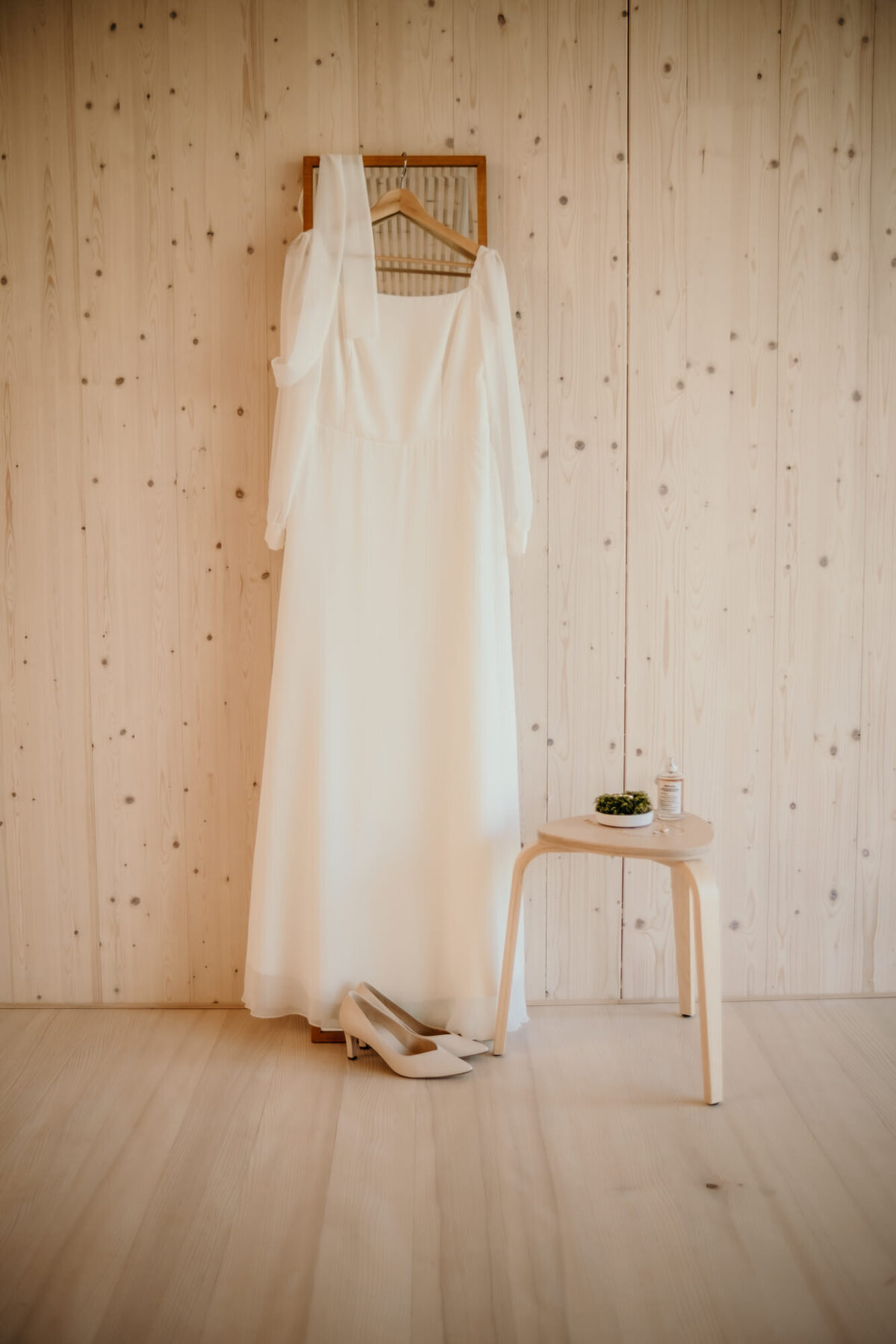 Bereit für den großen Tag hängt das Brautkleid an einem Kleiderbügel. Dabei stehen die Schuhe.