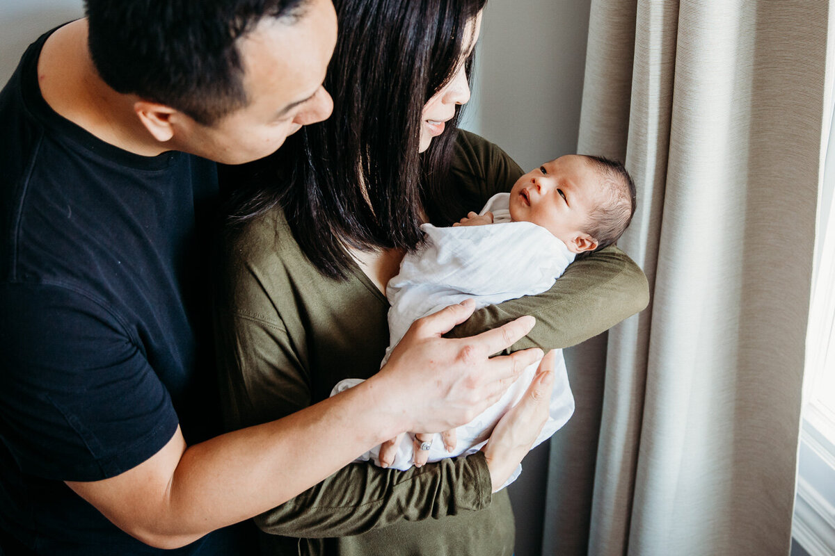 Parents holding awake baby boy during lifestyle newborn portrait session