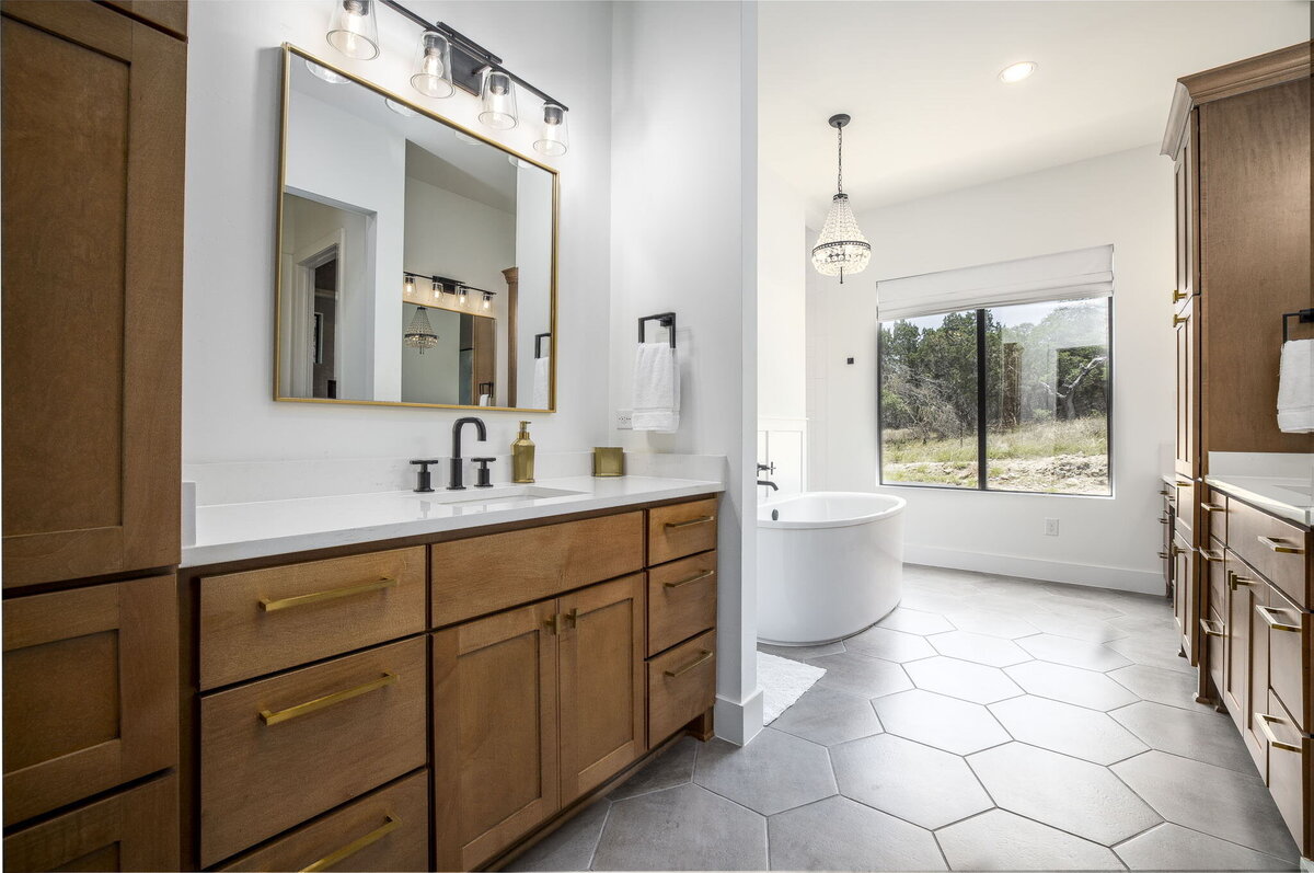 main bathroom with large hexagon tile floors, wood cabinets and free standing bathtub