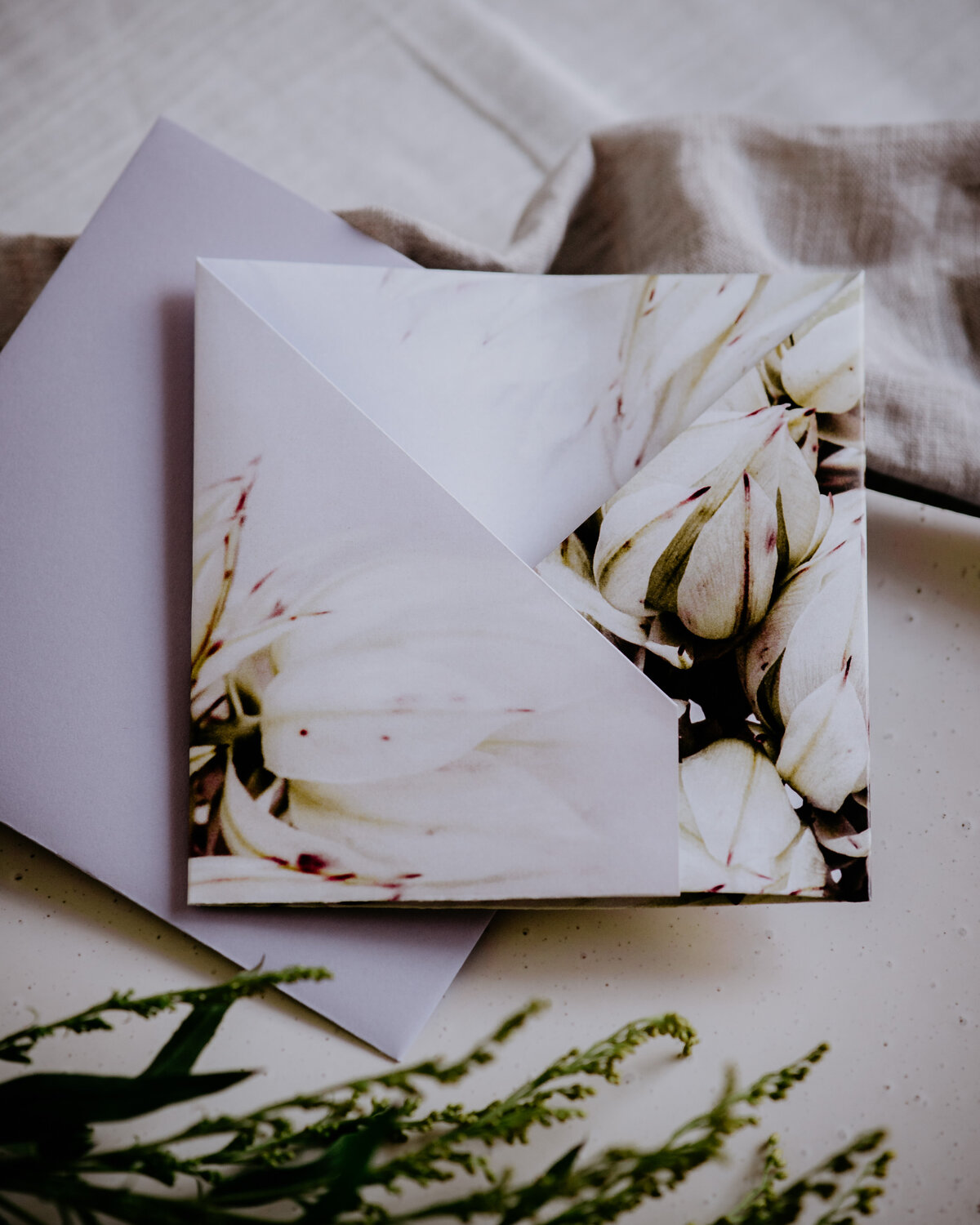 Delicate folded floral origami wedding invitation with cream flower photograph and lavender envelope