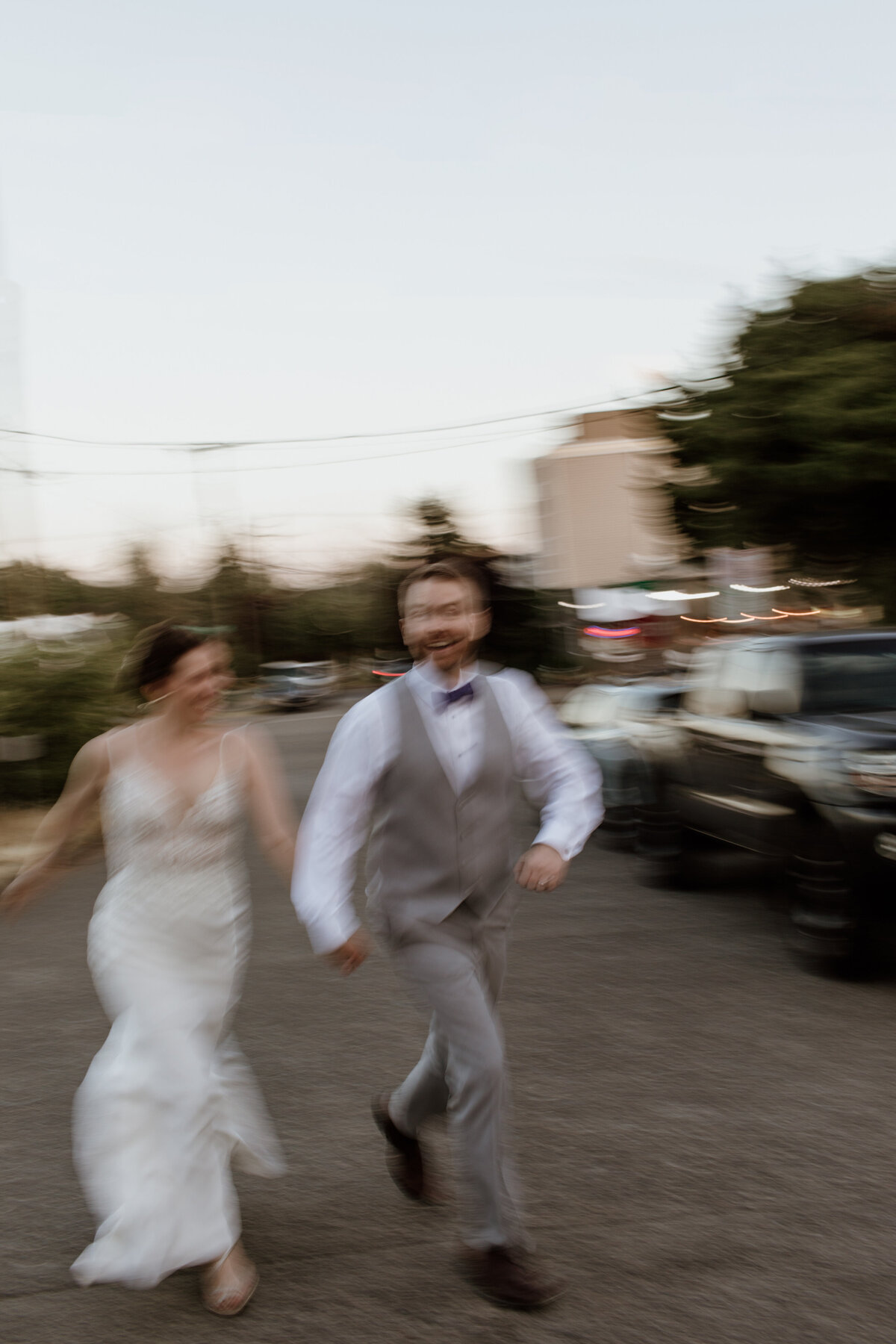 A blurry in motion moment of a happy couple in wedding attire as they run across a street. Captured by Fort Worth Wedding Photographer, Megan Christine Studio