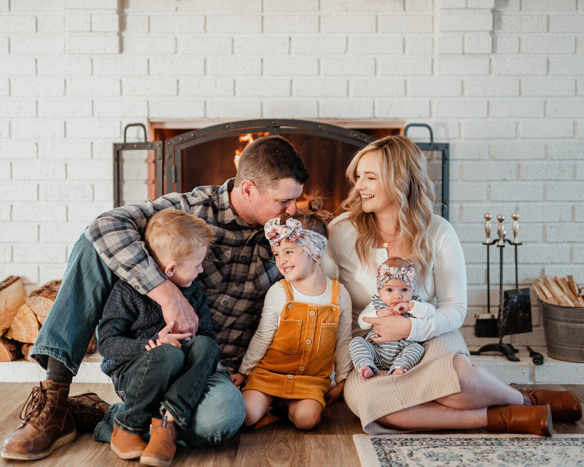 Family sitting by fireplace in Prescott, Arizona for in home photoshoot kids and babies