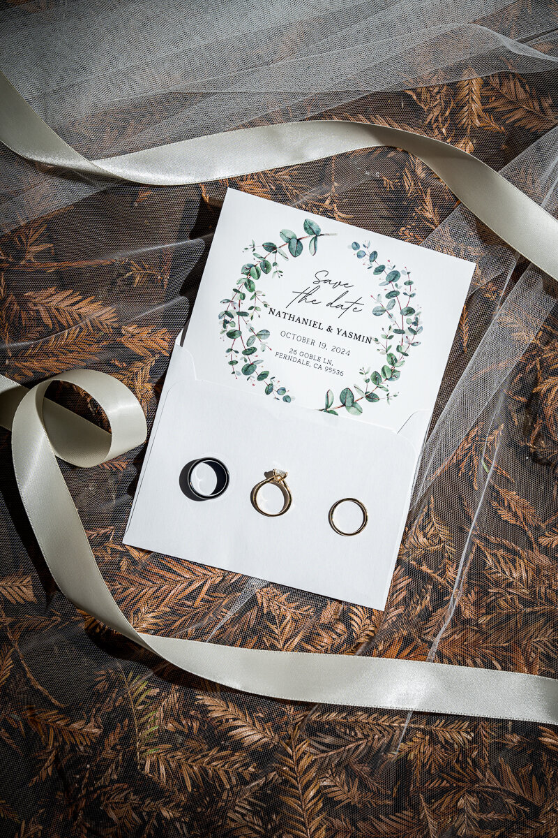 A stunning flat-lay of the bride's details, featuring her wedding rings, beautifully designed invitation suite, and delicate accessories in Fortuna, California. Capturing the essence of her big day, this elegant arrangement adds a personal and timeless touch to her wedding story. Perfect for showcasing bridal style and sentimental moments in Northern California weddings.
