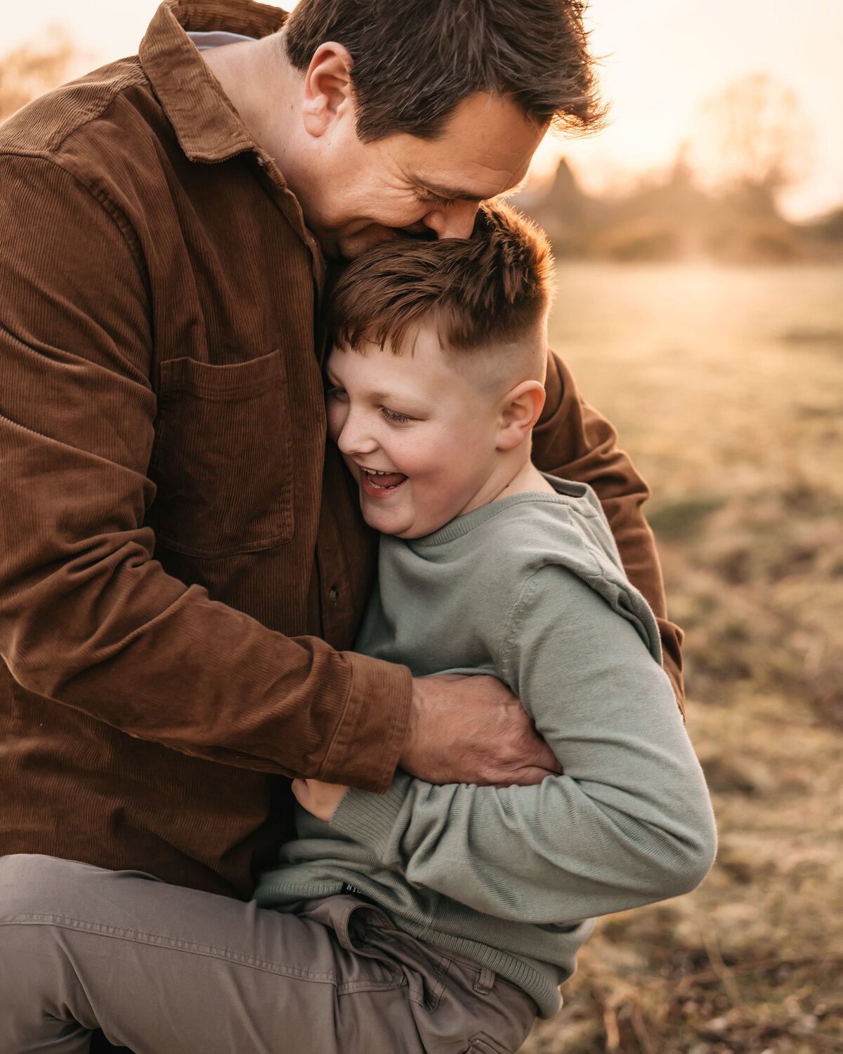 Photo of a father and son playing together and laughing outside at sunset during a family photoshoot in Shrewsbury