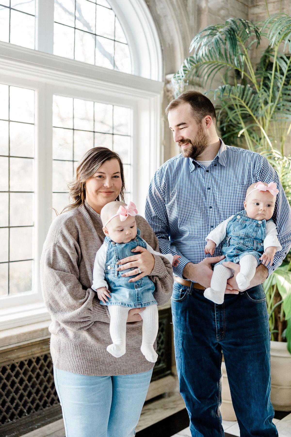 husband smiling at wife while they hold twin babies