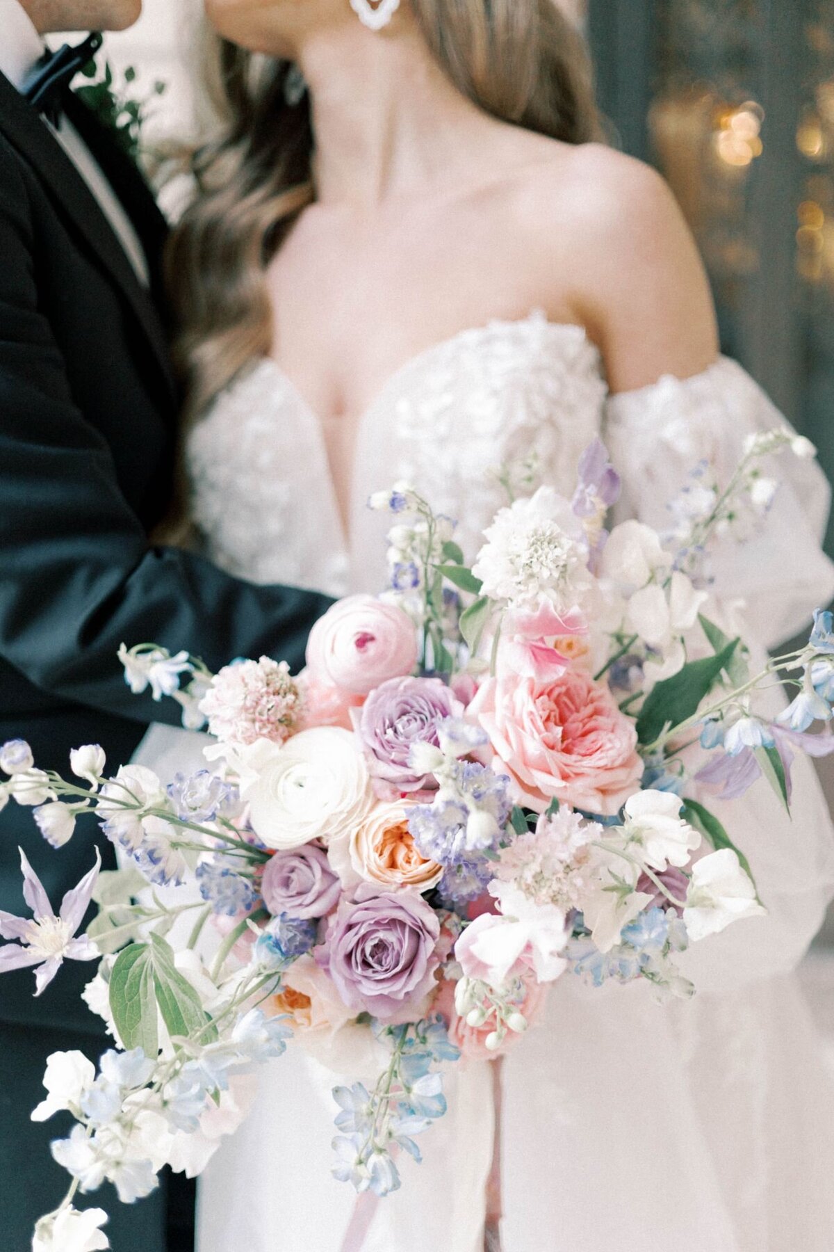 Close up shot of bride holding bouquet of flowers while she and the groom embrace each other.